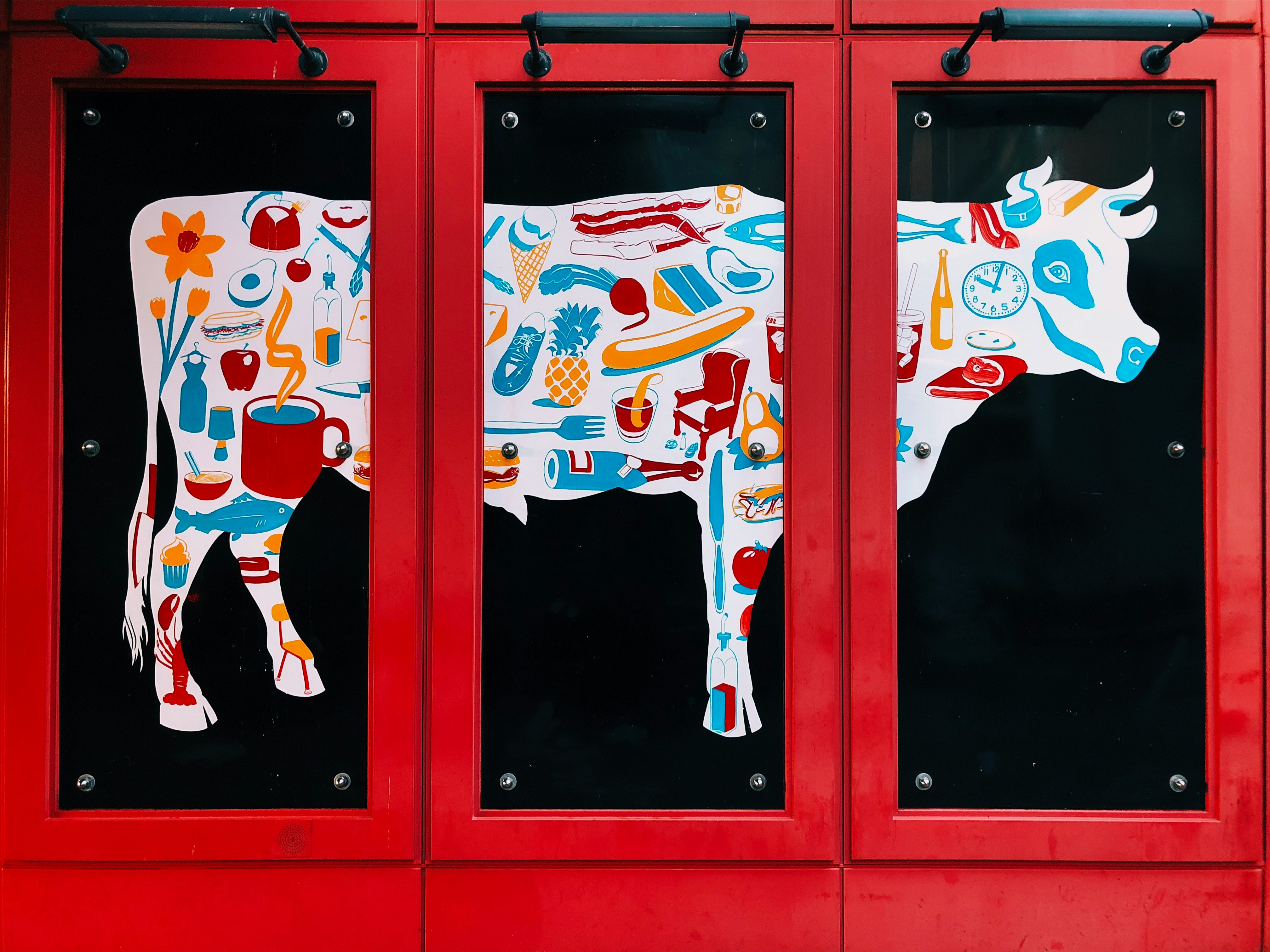 white, blue, and red cow 3-panel painting on wall